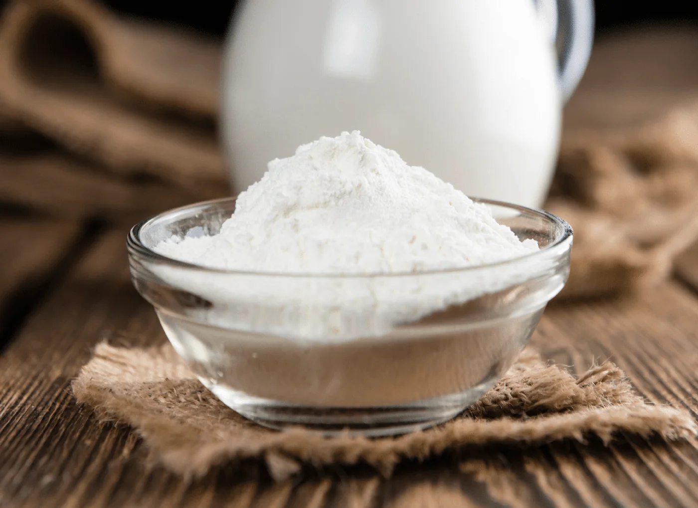 Colostrum powder in a bowl beside milk